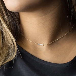 Elegant gold stainless steel necklace with five white beads worn by a female model