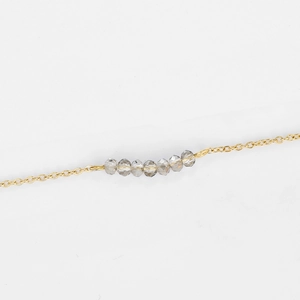 Collier minimaliste en acier doré avec sept perles de cristal gris facettées
