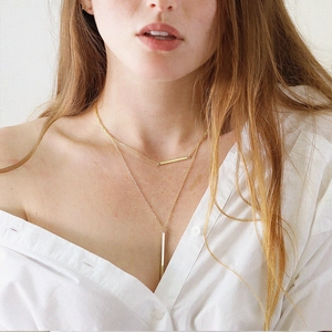 Minimalist gold bar layered necklace set with vertical and horizontal pendants on a model