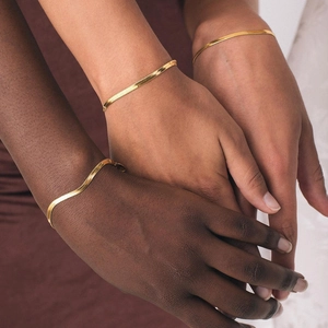 Nahaufnahme vergoldeter Schlangenkette-Armbänder aus Edelstahl auf verschiedenen Hauttönen