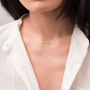 Nahaufnahme einer zarten Roségold-O-Kette mit einer weißen Perle an einem Model