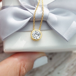 Macro detail of a 12-color rhinestone gold pendant necklace displayed on a white gift box