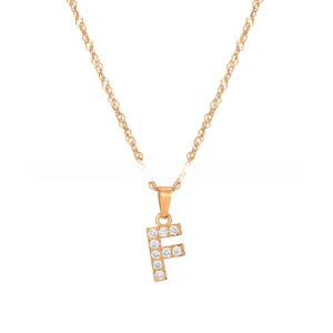 Macro shot of gold-plated letter F pendant featuring sparkling white rhinestones and a fine chain