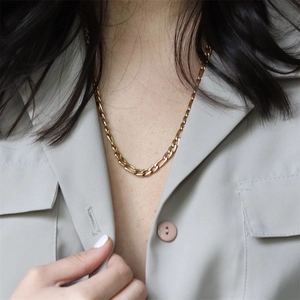 Elegant gold-plated Figaro chain necklace in stainless steel worn by a fashion model
