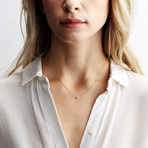 Minimalist freshwater pearl pendant on a gold chain necklace worn by a model