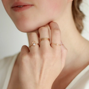 Detailed view of minimalist gold zircon rings worn on fingers in an elegant pose