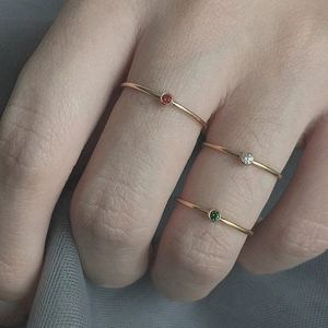 Detailed view of three slim stainless steel rings with red, white, and green zircons