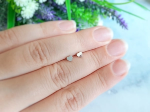 Gros plan de petites boucles d'oreilles cœur argentées montrant leur taille délicate