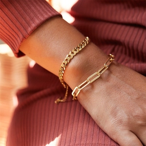 Close-up of gold layered curb chain and paperclip link bracelet set on woman's wrist