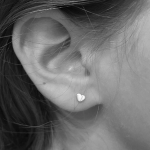 Gros plan d'une boucle d'oreille cœur minimaliste portée à l'oreille, vue de profil N&B