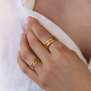 Close-up of gold chain link ring and thick band ring on hand for a layered jewelry look