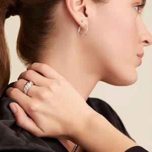 Detailed view of silver croissant ring with polished spiral texture worn by a model