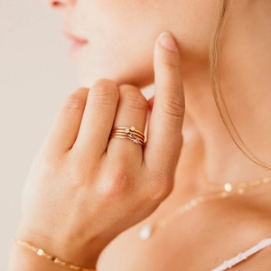 Close-up of four minimalist gold rings with colorful zircons worn on female fingers