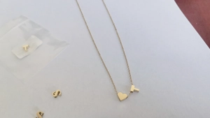 Détail du pendentif cœur doré avec la lettre T sur une fine chaîne en acier inoxydable