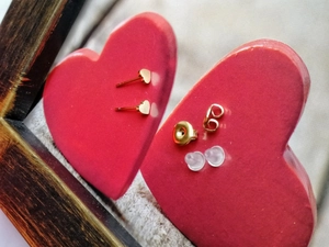 Puces d'oreilles cœur dorées avec fermoirs en métal et plastique sur décor cœur