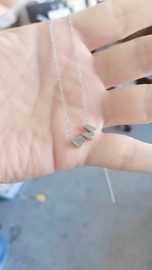 Détail du pendentif cœur et de la lettre M sur une chaîne en acier inoxydable argenté