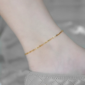 Nahaufnahme einer filigranen vergoldeten Edelstahl-Fußkette mit schimmerndem Spitzen-Design