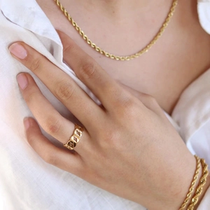 Close-up of gold chain ring and rope necklace set worn by a model in a white shirt