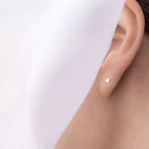 Clous d'oreilles minimalistes en forme de cœur plaqués or portés par un mannequin