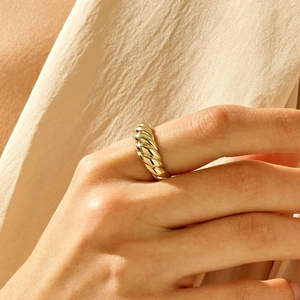 Polished gold croissant dome ring with twisted design worn on model with silk backdrop
