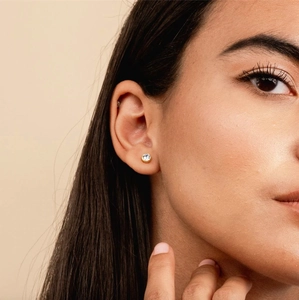 Close-up of a gold-plated stainless steel stud earring with a round clear zircon stone