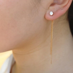 Boucles d'oreilles pendantes dorées avec zircon et longues chaînes portées par un modèle