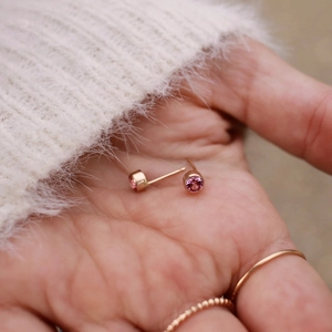 Macro shot of minimalist gold-plated stainless steel studs with pink cubic zirconia