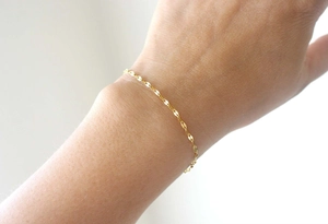 Close-up of a minimalist gold stainless steel shimmer chain bracelet on a wrist