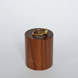 Detailed macro view of gold sunburst engraved ring on dark wood display stand