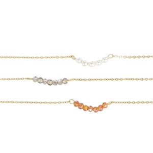 Trois colliers minimalistes en or avec perles blanches, cristaux gris et ambre en pendentif