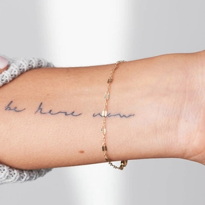 Close-up of a minimalist golden stainless steel lip link chain on a woman's wrist