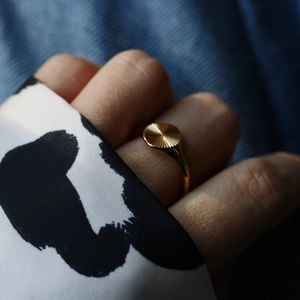 Detailed macro shot of gold textured ring with sunburst pattern on model finger