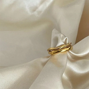 Detailed view of gold wavy rings nestled in elegant champagne silk fabric with soft lighting