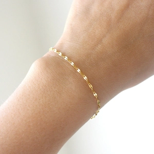Detailed close-up of a delicate gold stainless steel lace chain bracelet on a wrist
