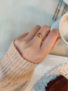 Detail view of a gold-plated sunburst textured ring worn in a cozy tea setting