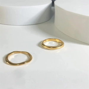 Macro detail of wave irregular texture on minimalist gold-plated stainless steel rings