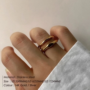 Close-up of minimalist wave stainless steel rings in 14K gold and silver finishes