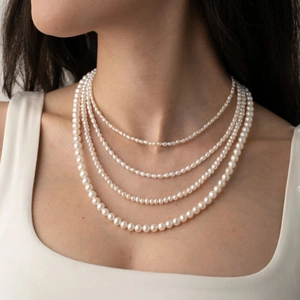 Detail of four-layer layered pearl necklace with 14K gold-plated clasp on model