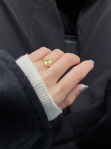 Detail of a gold stainless steel signet ring with sunburst texture on a model's hand
