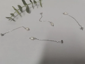 Detailed macro view of four freshwater pearl earrings with long silver-tone link chains
