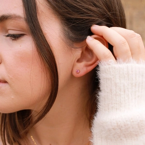 Close-up of bezel-set pink gemstone stud earring in gold plated stainless steel
