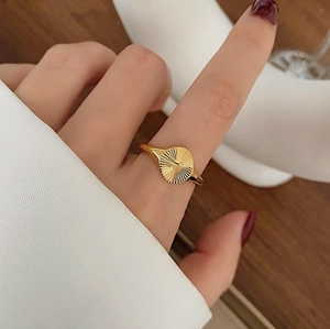Detailed close-up of golden ring featuring sunburst texture and minimalist round design