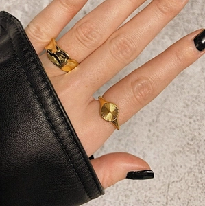 Detailed view of gold lava texture band and sunburst engraved signet rings set
