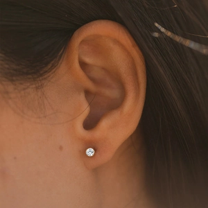 Gros plan d'une boucle d'oreille ronde en cristal avec serti clos en acier plaqué or