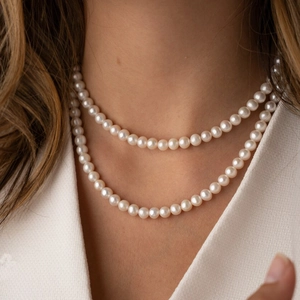 Close-up of double-layer faux pearl necklace with warm milky white luster on a model
