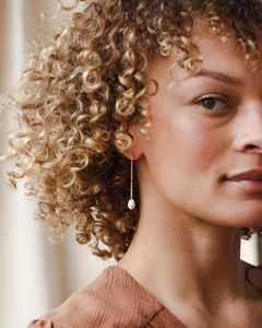 Close-up of gold chain earrings with baroque pearls on model for elegant styling