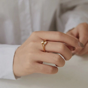 Close-up of golden signet ring with radial sunburst texture on a minimalist model background