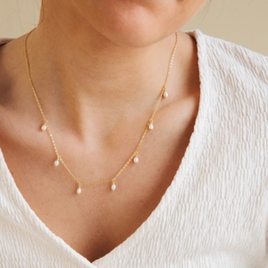Elegant gold-plated stainless steel necklace featuring seven delicate pearl drops on model