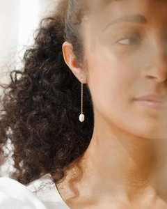 Close-up of elegant gold long chain drop earrings with white pearls worn by a model