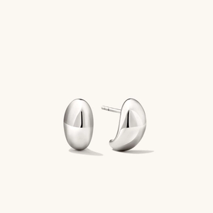 Détail macro de boucles d'oreilles argentées polies au design bombé et brillant